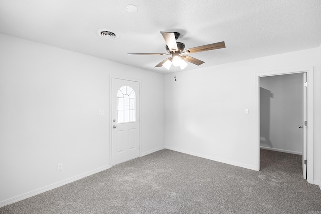 carpeted empty room featuring baseboards, visible vents, ceiling fan, and a textured ceiling