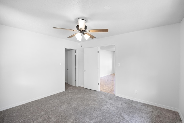 carpeted empty room featuring a ceiling fan and baseboards