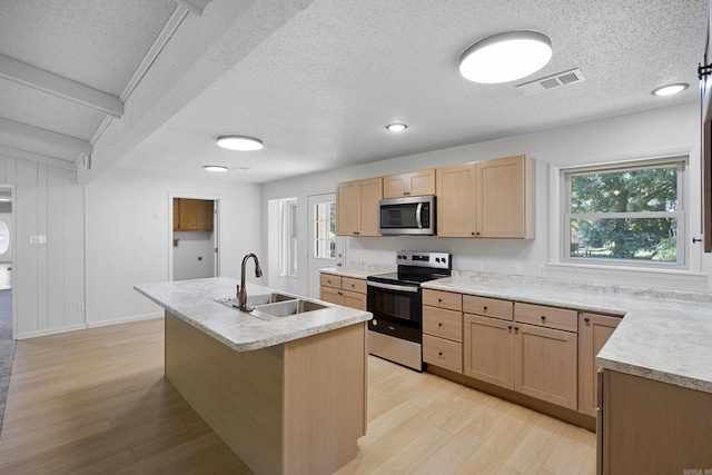 kitchen featuring stainless steel appliances, light countertops, visible vents, light wood-style floors, and a sink