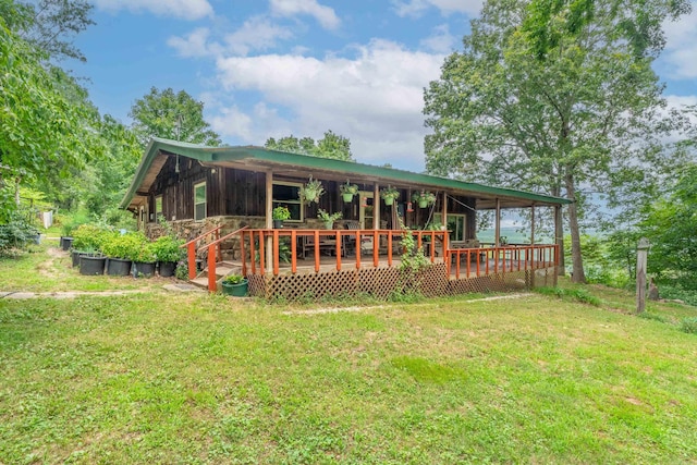 rear view of house featuring a lawn and a wooden deck