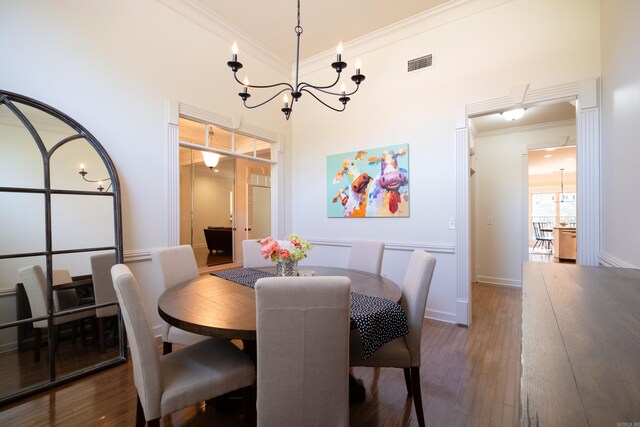 dining area featuring dark hardwood / wood-style flooring, ornamental molding, a high ceiling, and an inviting chandelier