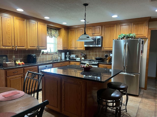 kitchen featuring appliances with stainless steel finishes, hanging light fixtures, light tile patterned flooring, tasteful backsplash, and a kitchen island