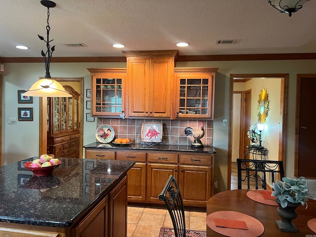 kitchen with tasteful backsplash, a textured ceiling, ornamental molding, light tile patterned floors, and a kitchen island