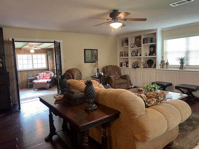 living room with ceiling fan, hardwood / wood-style flooring, and a textured ceiling