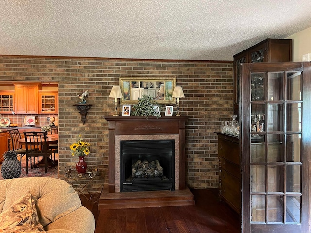 living room featuring a textured ceiling, hardwood / wood-style floors, and brick wall