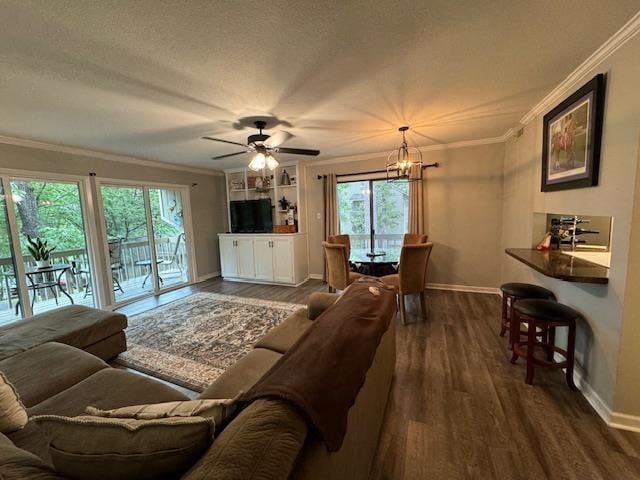 living room with crown molding, dark wood-type flooring, ceiling fan with notable chandelier, and a textured ceiling