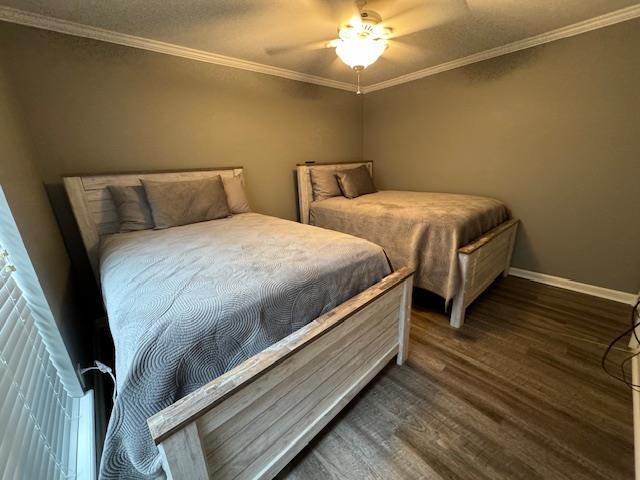 bedroom with ornamental molding, dark hardwood / wood-style floors, and ceiling fan