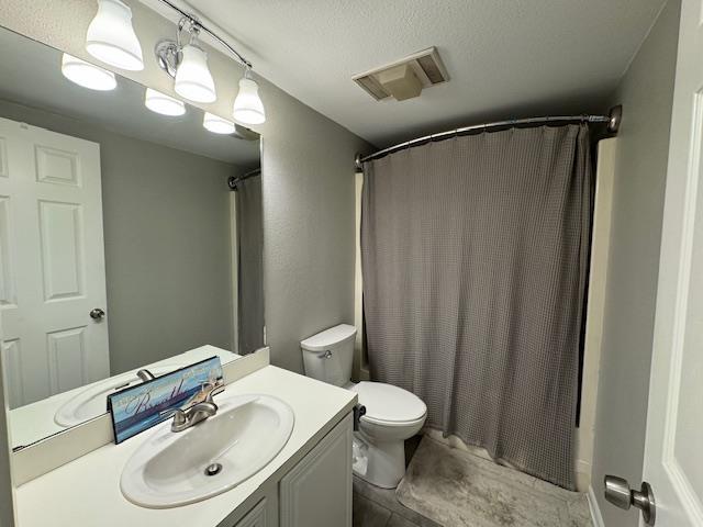 full bathroom featuring vanity, shower / bath combo with shower curtain, a textured ceiling, and toilet