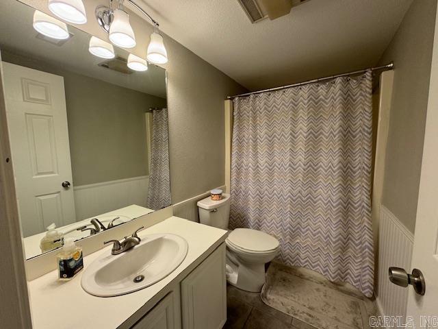 bathroom featuring vanity, walk in shower, toilet, tile patterned floors, and a textured ceiling