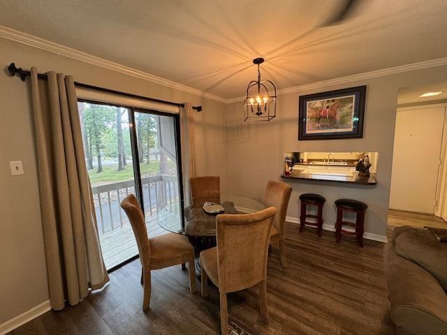 dining space with dark hardwood / wood-style flooring, a notable chandelier, and ornamental molding