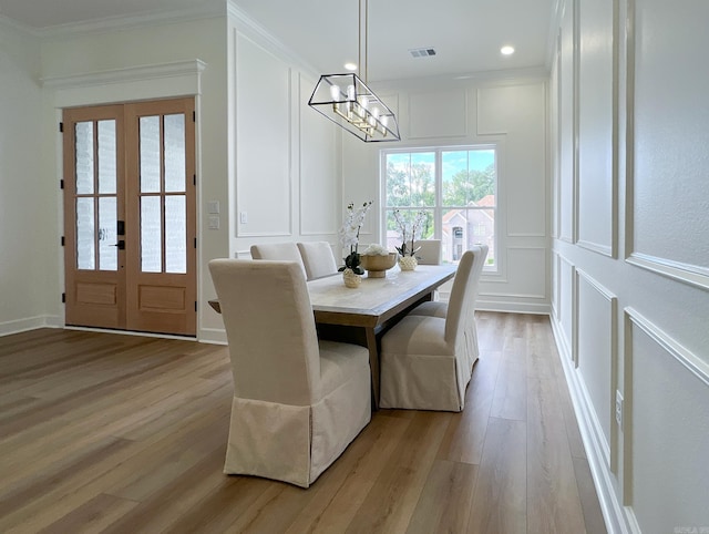 dining space featuring crown molding, light hardwood / wood-style flooring, french doors, and a chandelier