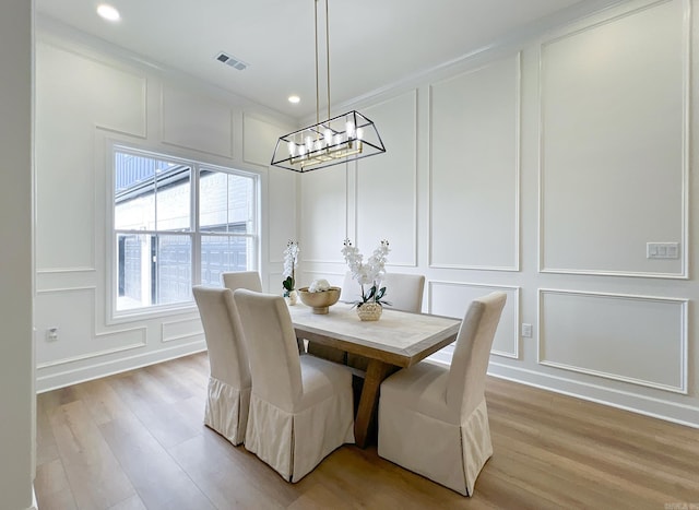 dining area with a notable chandelier, ornamental molding, and light wood-type flooring