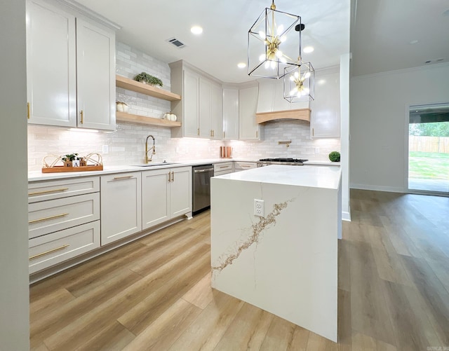 kitchen with sink, dishwasher, white cabinetry, hanging light fixtures, and light hardwood / wood-style floors