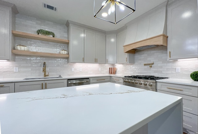 kitchen with light stone countertops, backsplash, stainless steel appliances, and sink