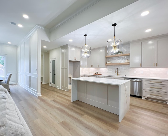 kitchen with sink, white cabinetry, decorative light fixtures, stainless steel dishwasher, and backsplash