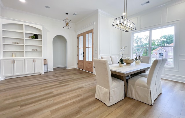 dining room featuring crown molding, a healthy amount of sunlight, built in features, and light hardwood / wood-style flooring