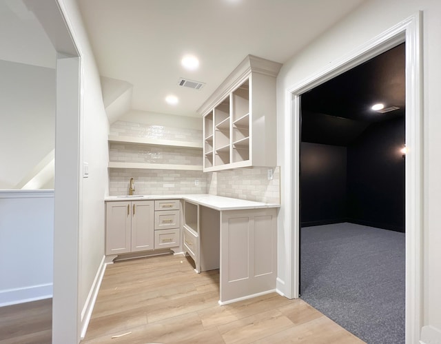 bar with light hardwood / wood-style floors, sink, decorative backsplash, and white cabinets