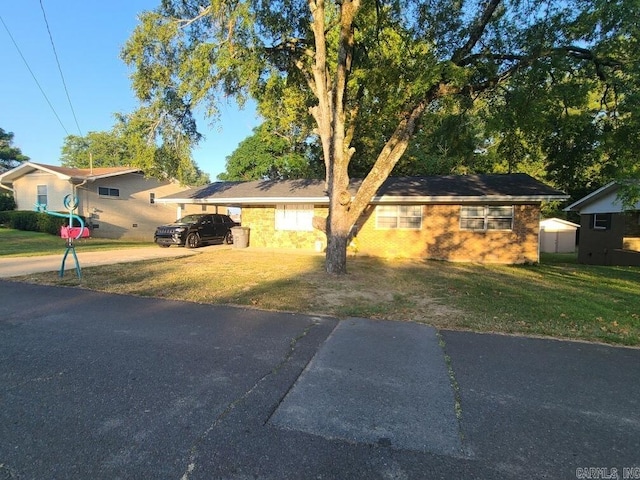 single story home featuring a front yard and a storage unit