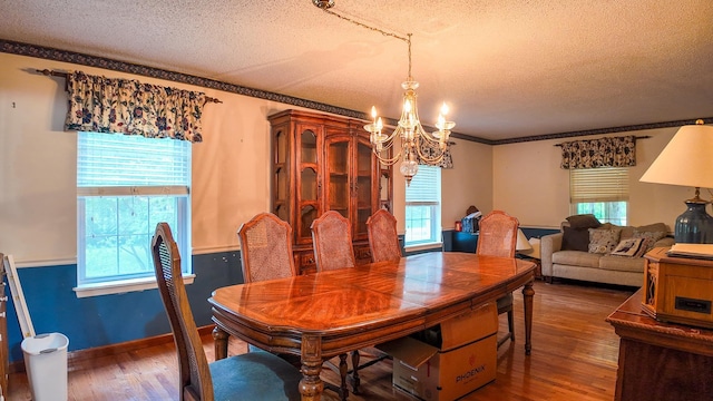 dining room with ornamental molding, dark hardwood / wood-style flooring, a chandelier, and a textured ceiling