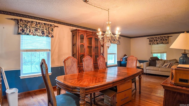 dining room with a textured ceiling, ornamental molding, dark hardwood / wood-style floors, and a chandelier