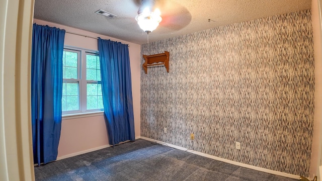 unfurnished room with dark carpet and a textured ceiling