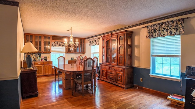 dining area featuring hardwood / wood-style flooring, a textured ceiling, and a chandelier