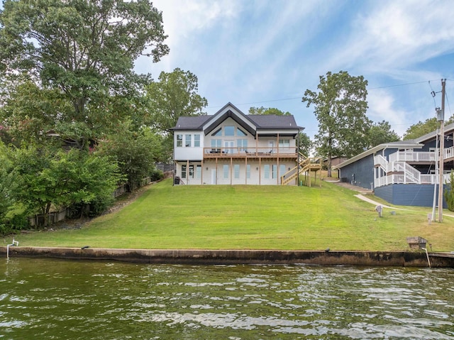 back of property with a lawn and a water view