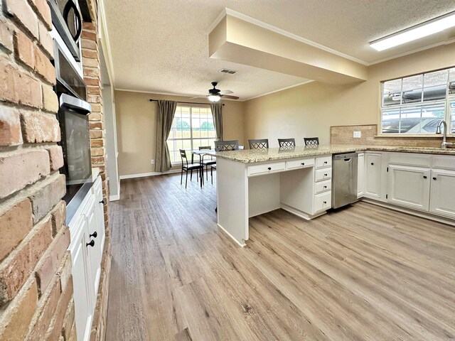 kitchen with a textured ceiling, kitchen peninsula, and light hardwood / wood-style floors