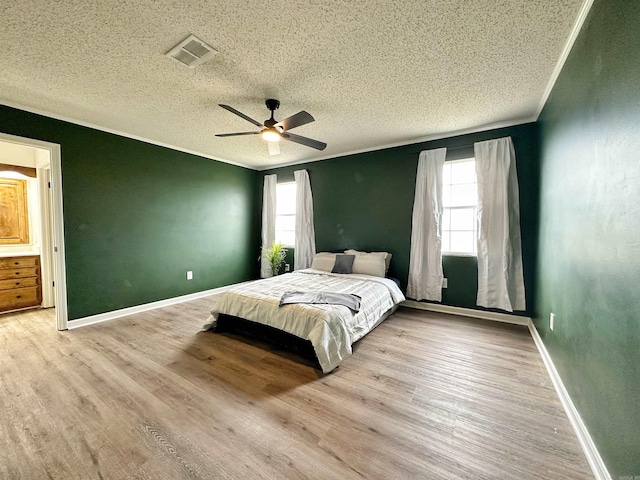 bedroom with ceiling fan, a textured ceiling, multiple windows, and light hardwood / wood-style floors