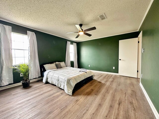 bedroom with ceiling fan, light wood-type flooring, and a textured ceiling