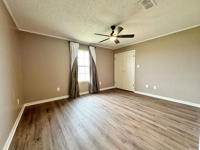 unfurnished bedroom with a textured ceiling, light wood-type flooring, crown molding, and ceiling fan