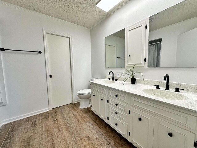 bathroom featuring hardwood / wood-style floors, a textured ceiling, double vanity, and toilet