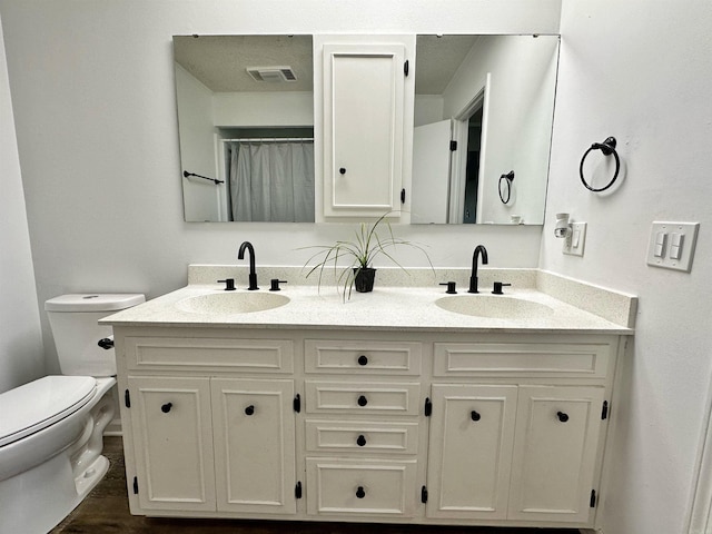 bathroom featuring hardwood / wood-style flooring, dual vanity, and toilet