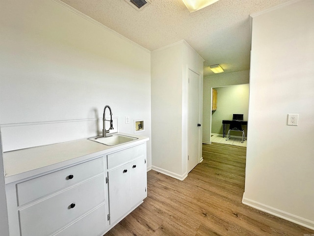 bar with light hardwood / wood-style flooring, a textured ceiling, sink, and white cabinetry