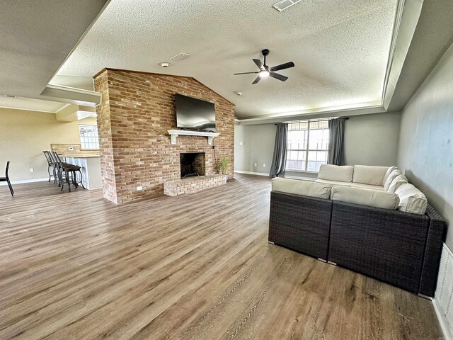 living room with ceiling fan, light hardwood / wood-style floors, and a brick fireplace