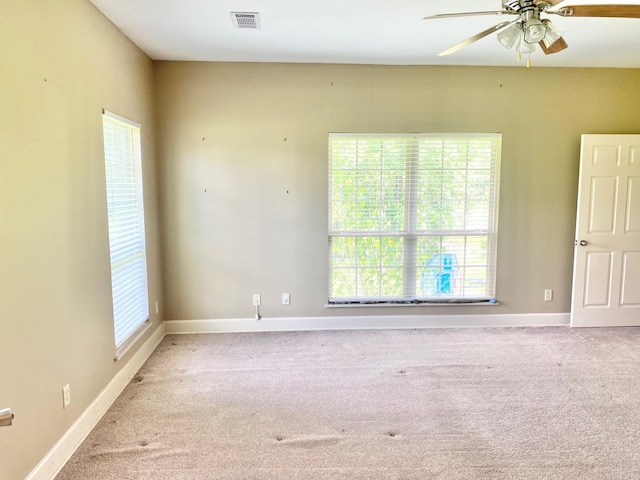 unfurnished room with ceiling fan, light colored carpet, and plenty of natural light