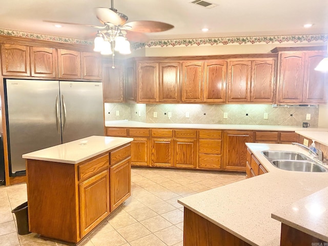 kitchen with ceiling fan, light tile patterned floors, a center island with sink, and backsplash