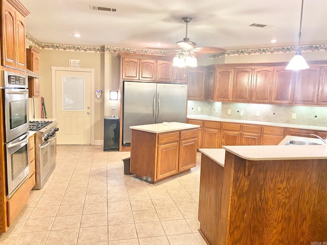 kitchen featuring appliances with stainless steel finishes, a center island, decorative light fixtures, backsplash, and sink