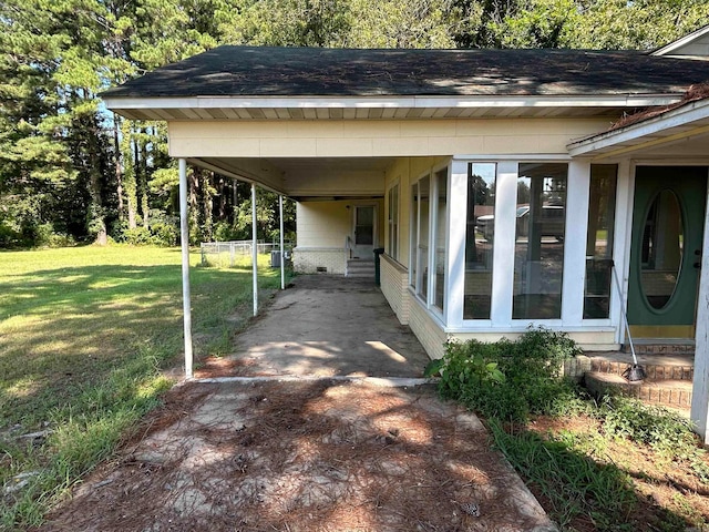 exterior space with a carport and a lawn