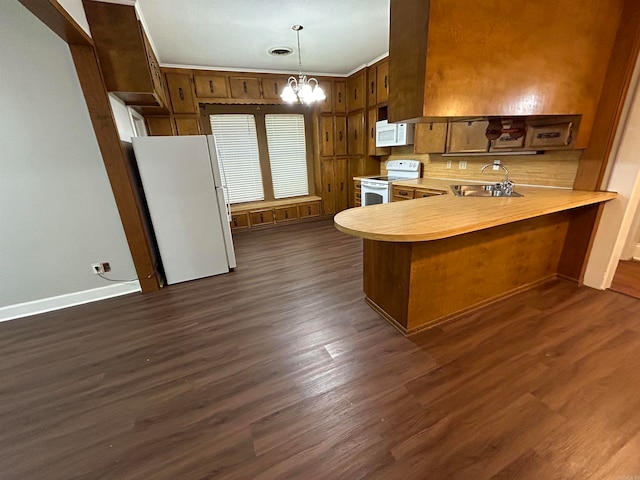 kitchen with kitchen peninsula, dark hardwood / wood-style floors, and white appliances