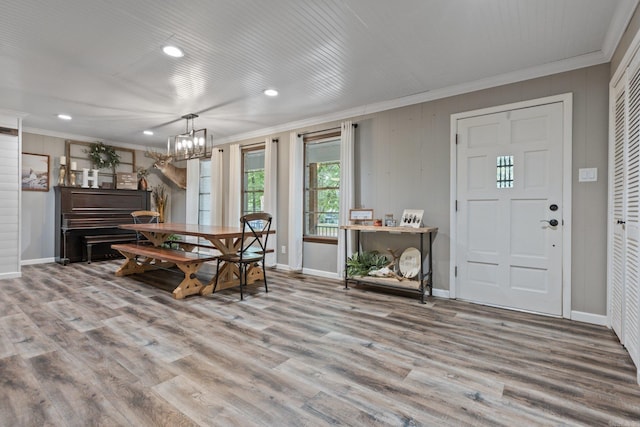 dining space with an inviting chandelier, ornamental molding, and hardwood / wood-style flooring