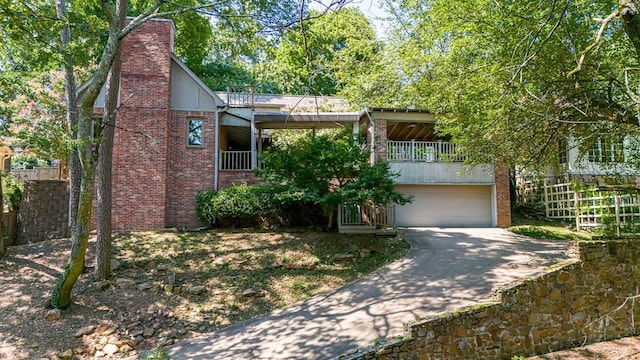 view of front of house with an attached garage, a chimney, concrete driveway, and brick siding