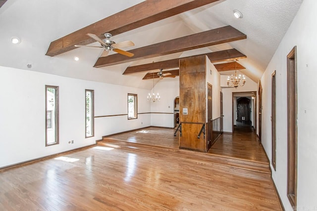 empty room with lofted ceiling with beams, arched walkways, ceiling fan with notable chandelier, wood finished floors, and baseboards