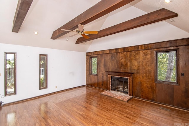 unfurnished living room with visible vents, a fireplace, lofted ceiling with beams, and wood finished floors