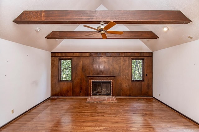 unfurnished living room featuring a fireplace, lofted ceiling with beams, and wood finished floors