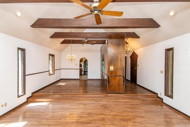 empty room with lofted ceiling with beams, wood finished floors, arched walkways, and baseboards