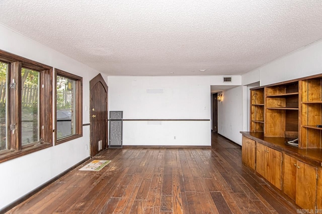 spare room with dark wood-style floors, baseboards, and a textured ceiling