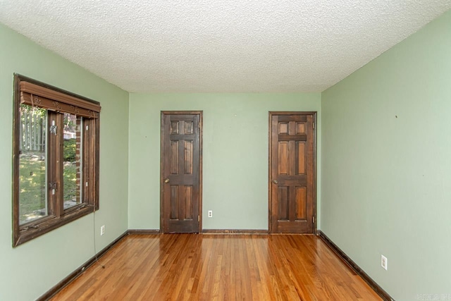 unfurnished bedroom featuring baseboards, light wood-style flooring, and a textured ceiling