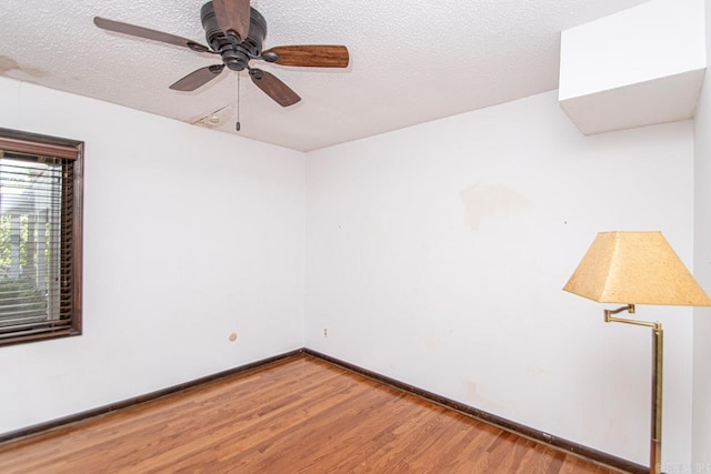 empty room featuring ceiling fan, a textured ceiling, baseboards, and wood finished floors