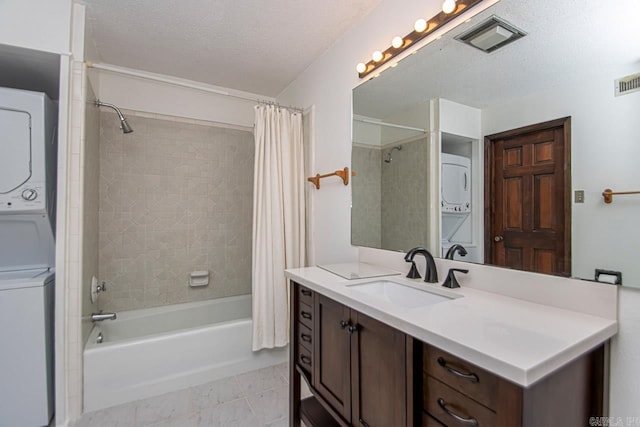 bathroom featuring visible vents, stacked washer / drying machine, shower / bath combo with shower curtain, a textured ceiling, and vanity